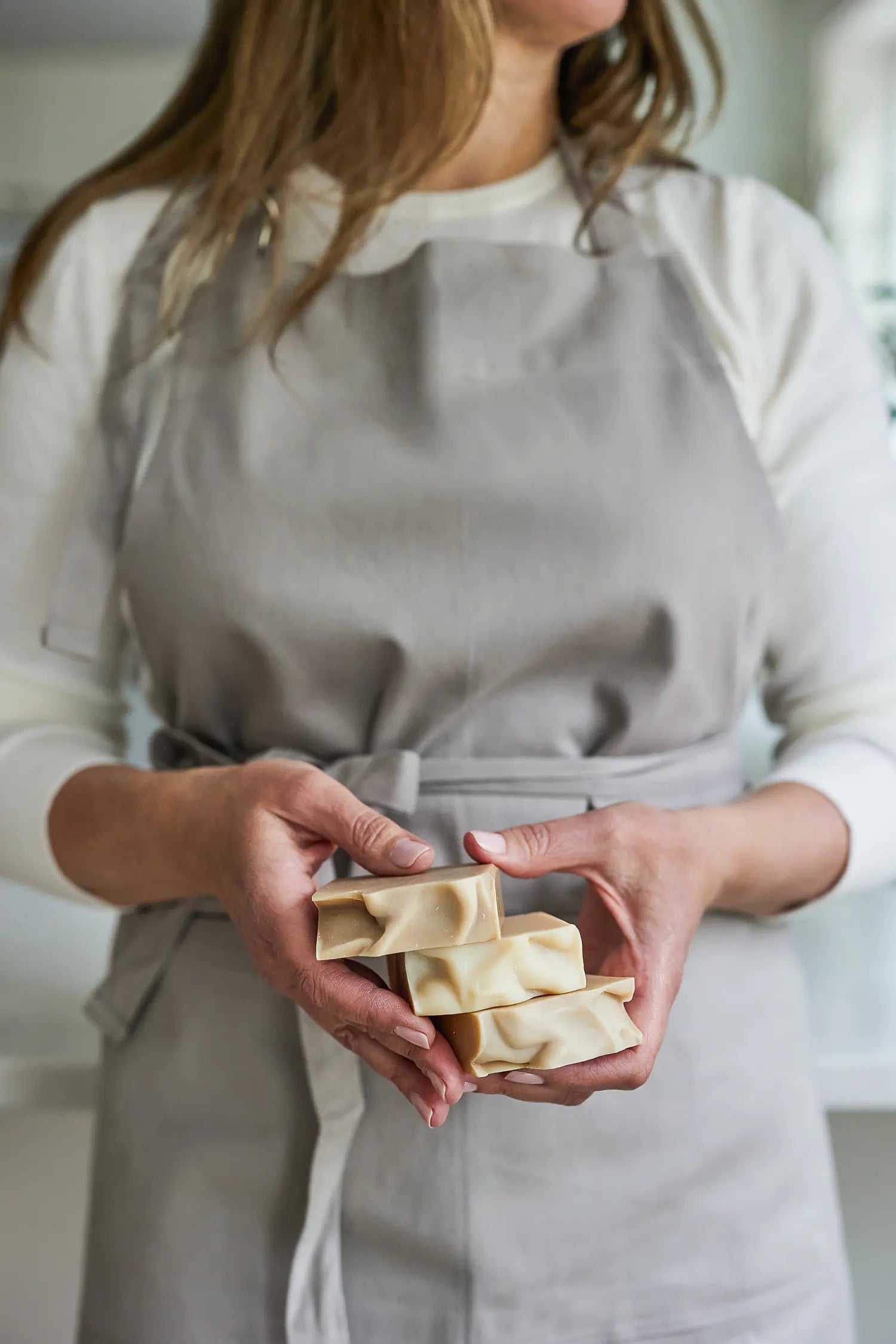 Closeup of Juniper Loft founder Christina holding three bars of goat milk soap