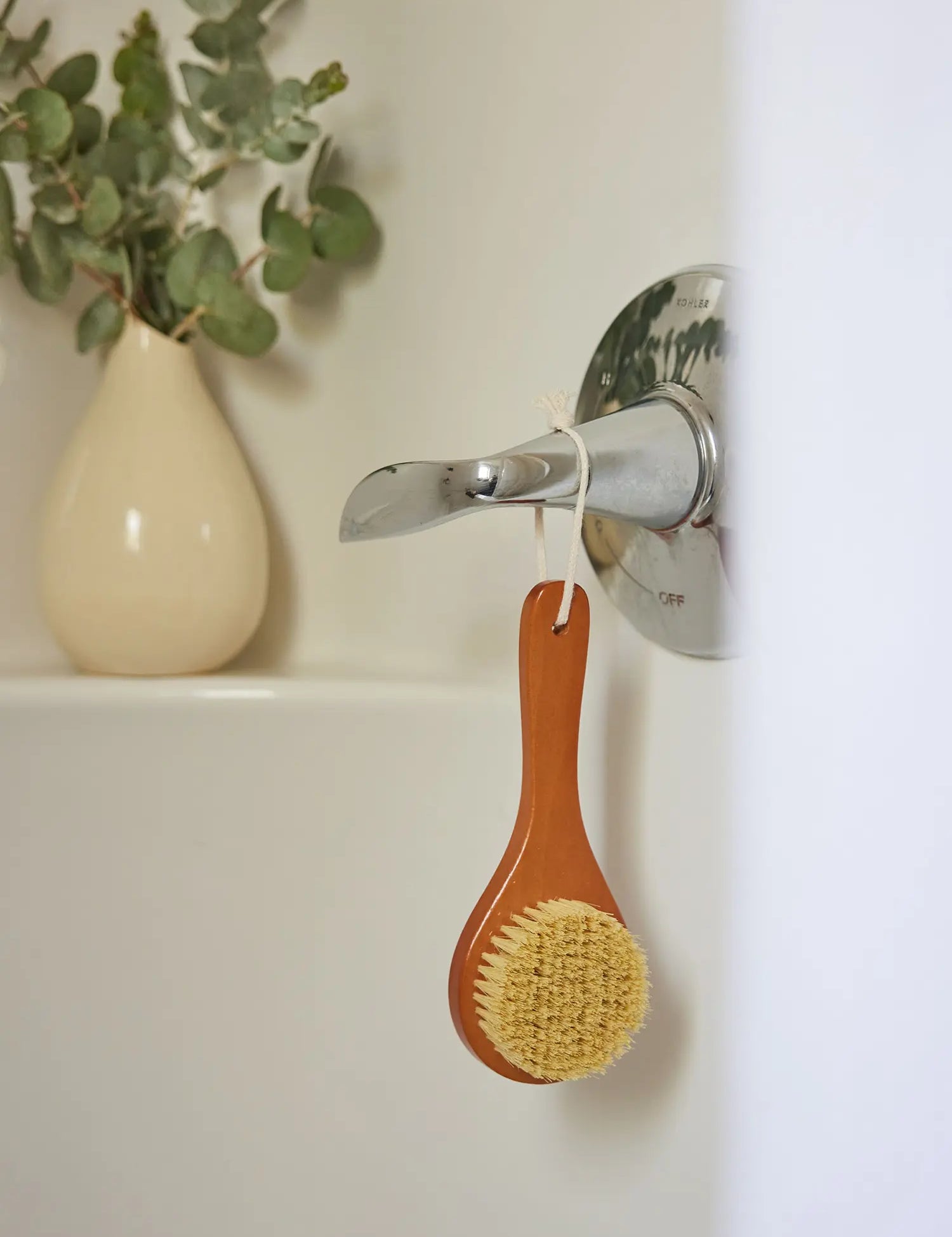 Juniper Loft Soap Company dry body brush hanging from a bathtub lever