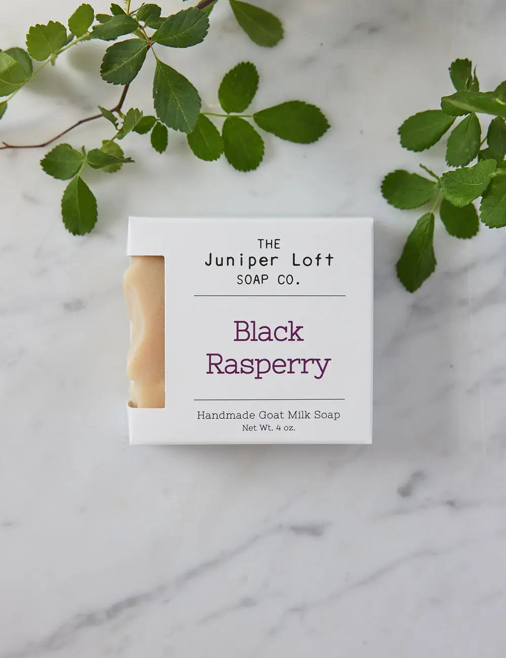 Bar of Black Raspberry soap from Juniper Loft Soap Company with some raspberry leaves around it