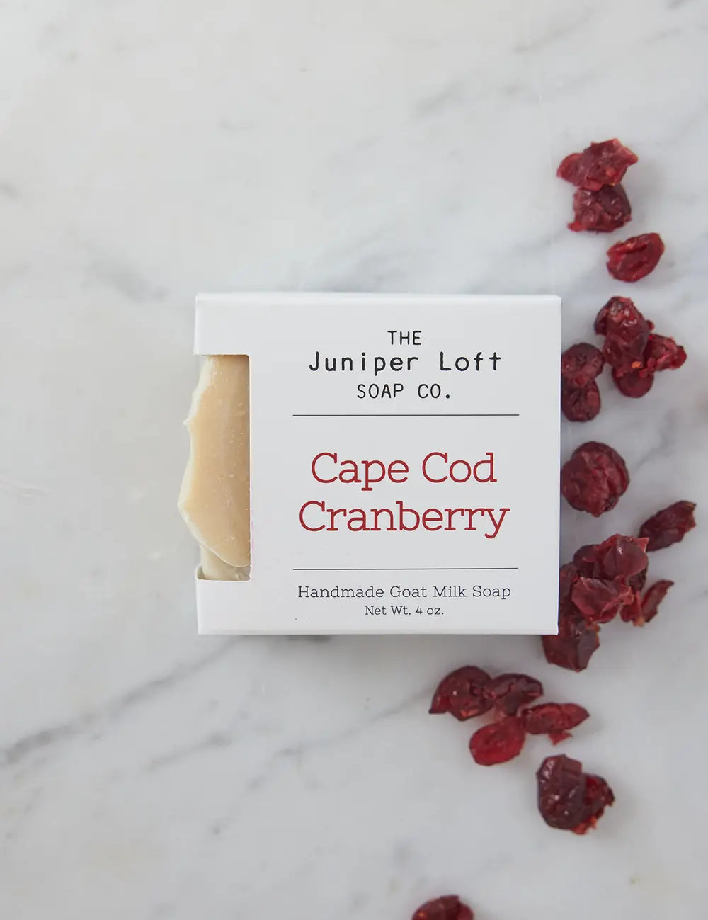Bar of Cape Cod Cranberry soap from Juniper Loft Soap Company next to a handful of dried cranberries
