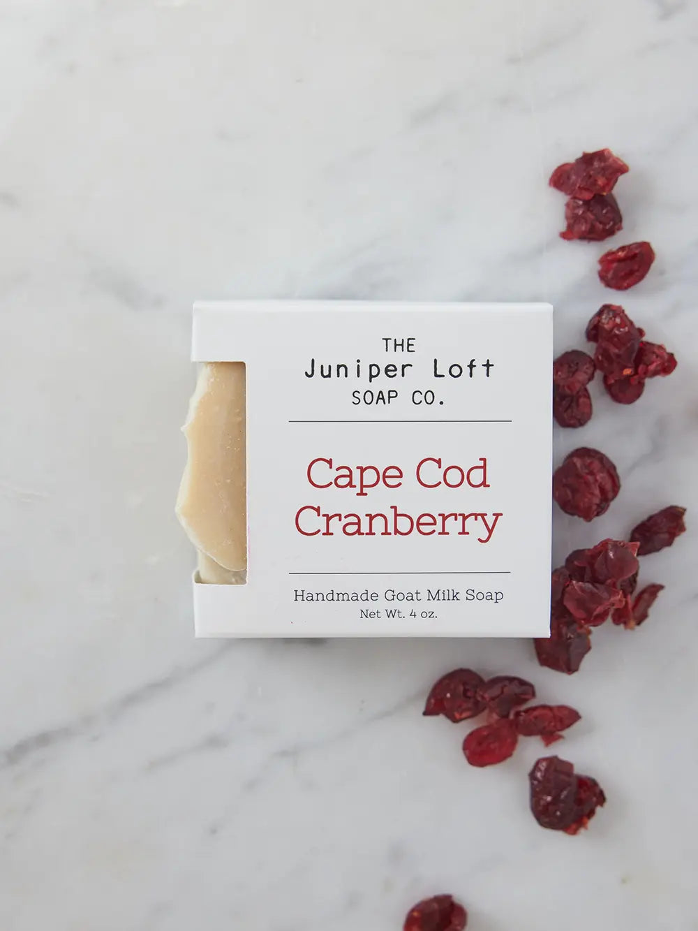 Bar of Cape Cod Cranberry soap from Juniper Loft Soap Company next to a handful of dried cranberries