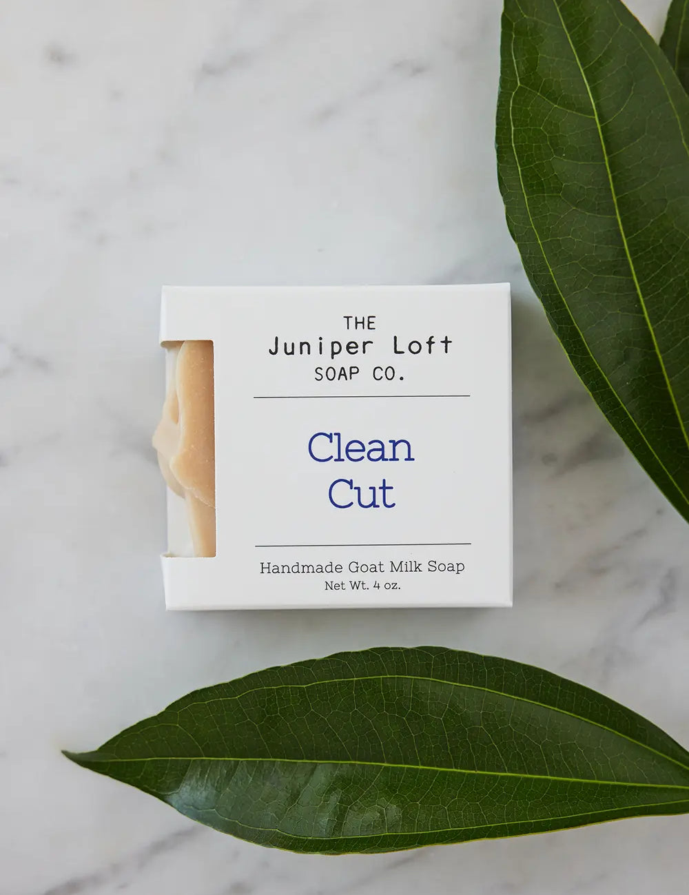 Two large green leaves around a bar of Clean Cut soap from Juniper Loft Soap Company