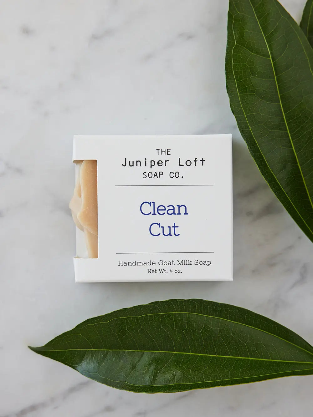 Two large green leaves around a bar of Clean Cut soap from Juniper Loft Soap Company