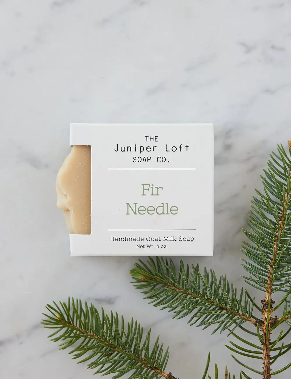 Bar of Fir Needle soap from Juniper Loft Soap Company next to a small branch of fir needles