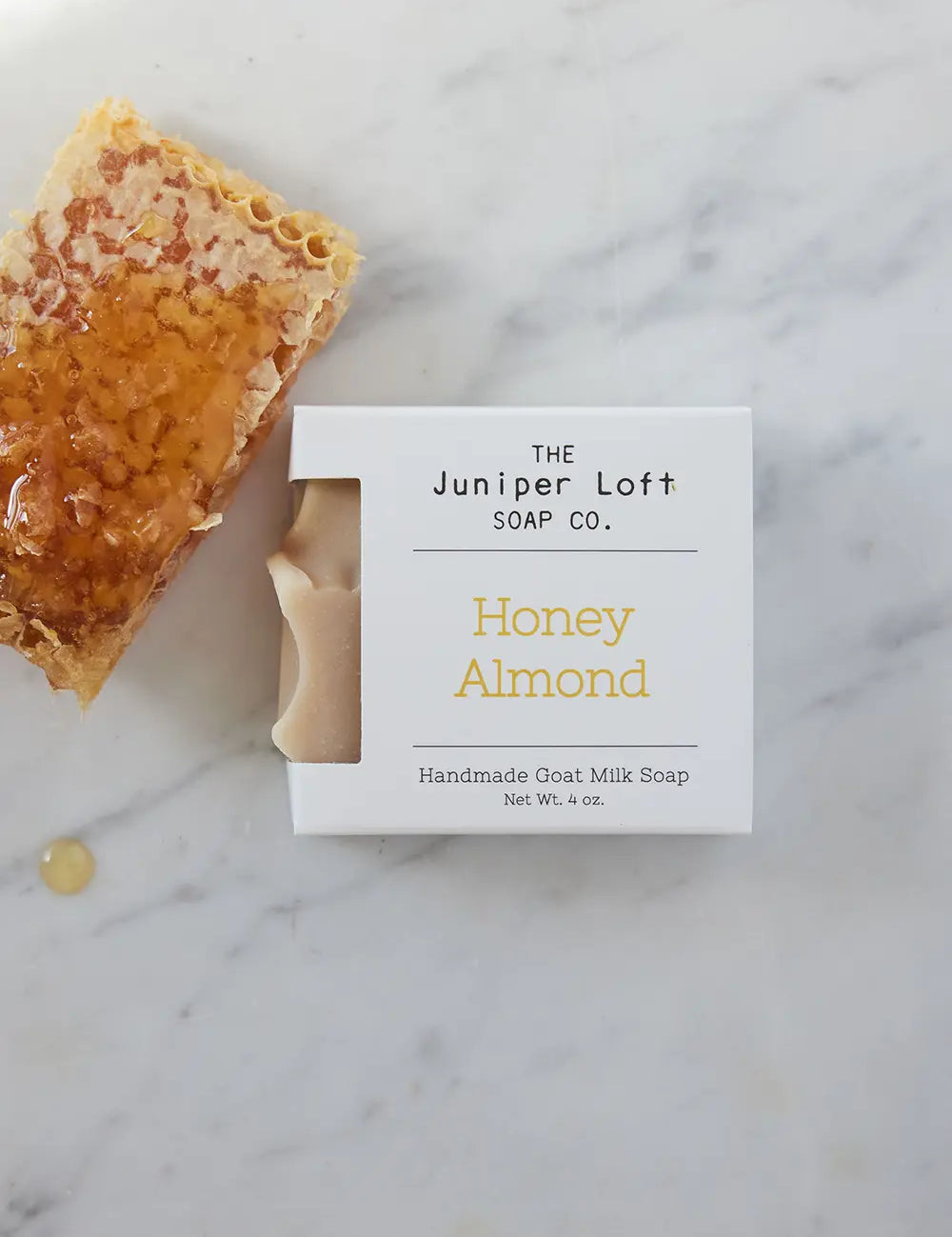 Bar of Honey Almond soap from Juniper Loft Soap Company next to a piece of raw honeycomb