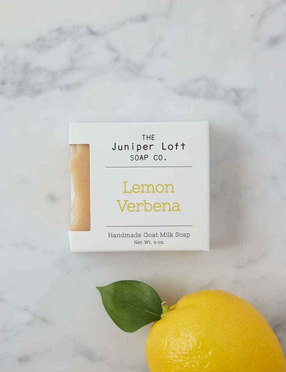 Bar of Lemon Verbena soap from Juniper Loft Soap Company next to a bright lemon