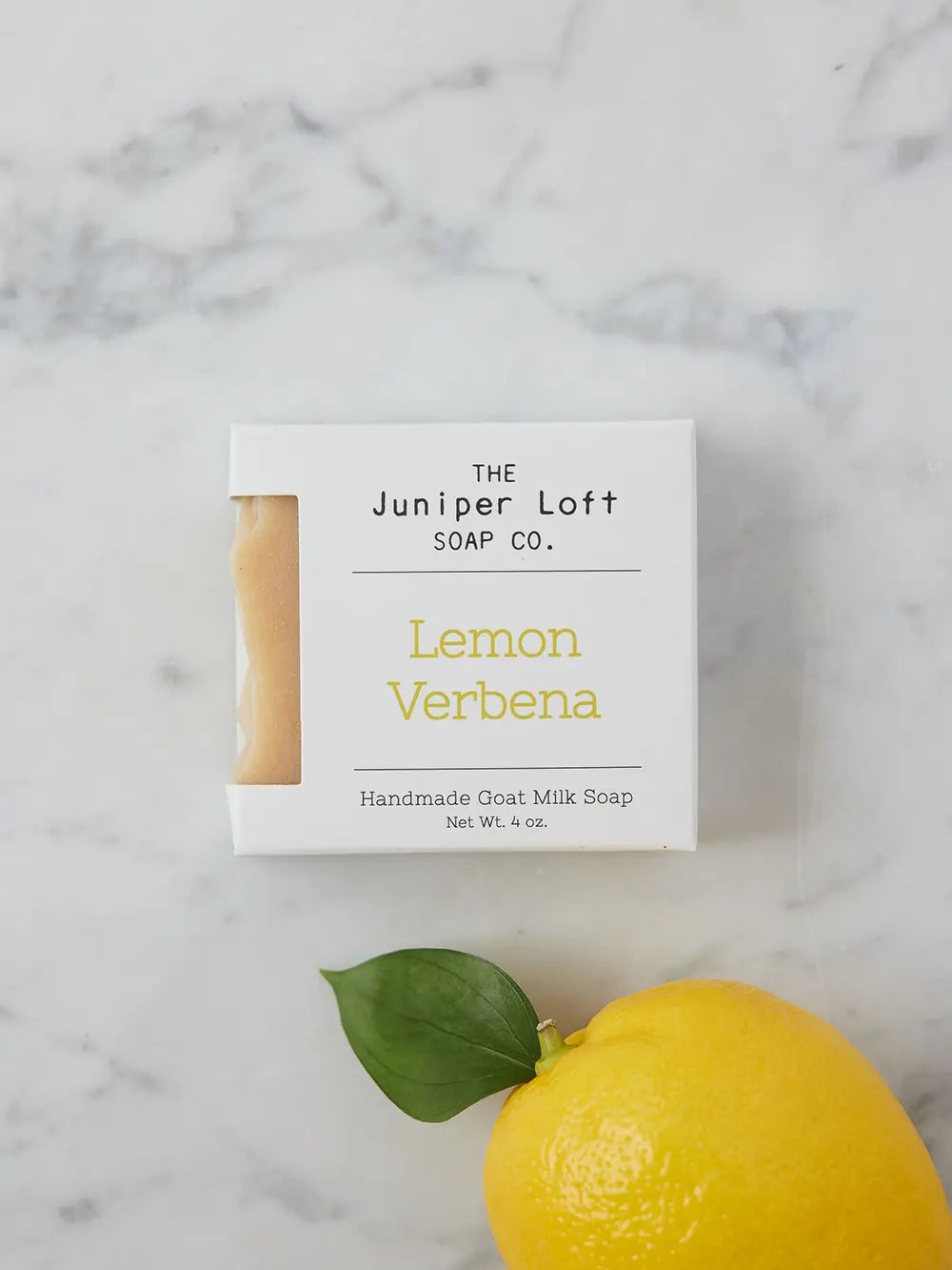 Bar of Lemon Verbena soap from Juniper Loft Soap Company next to a bright lemon