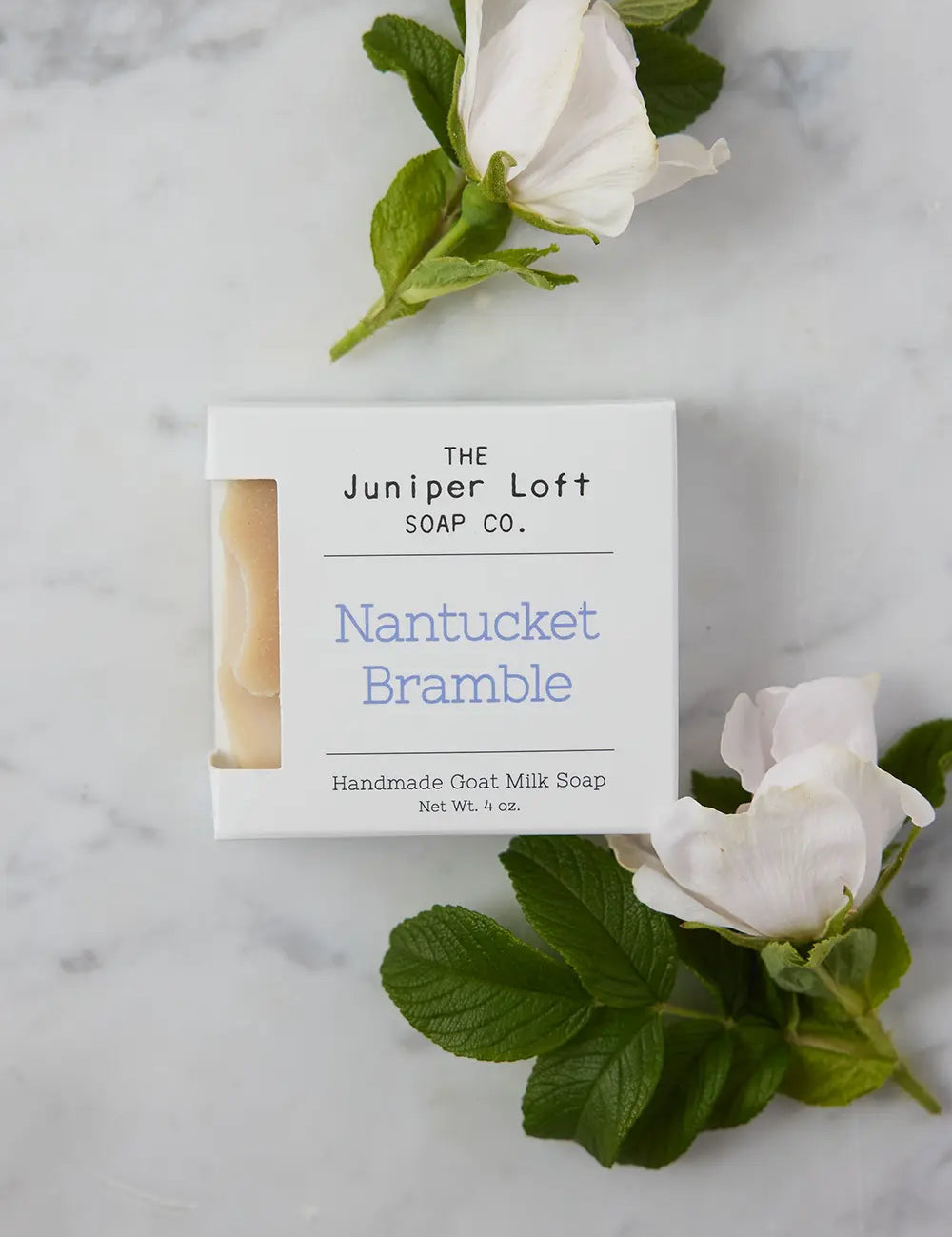 Bar of Nantucket Bramble soap from Juniper Loft Soap Company next to two brambleberry flowers