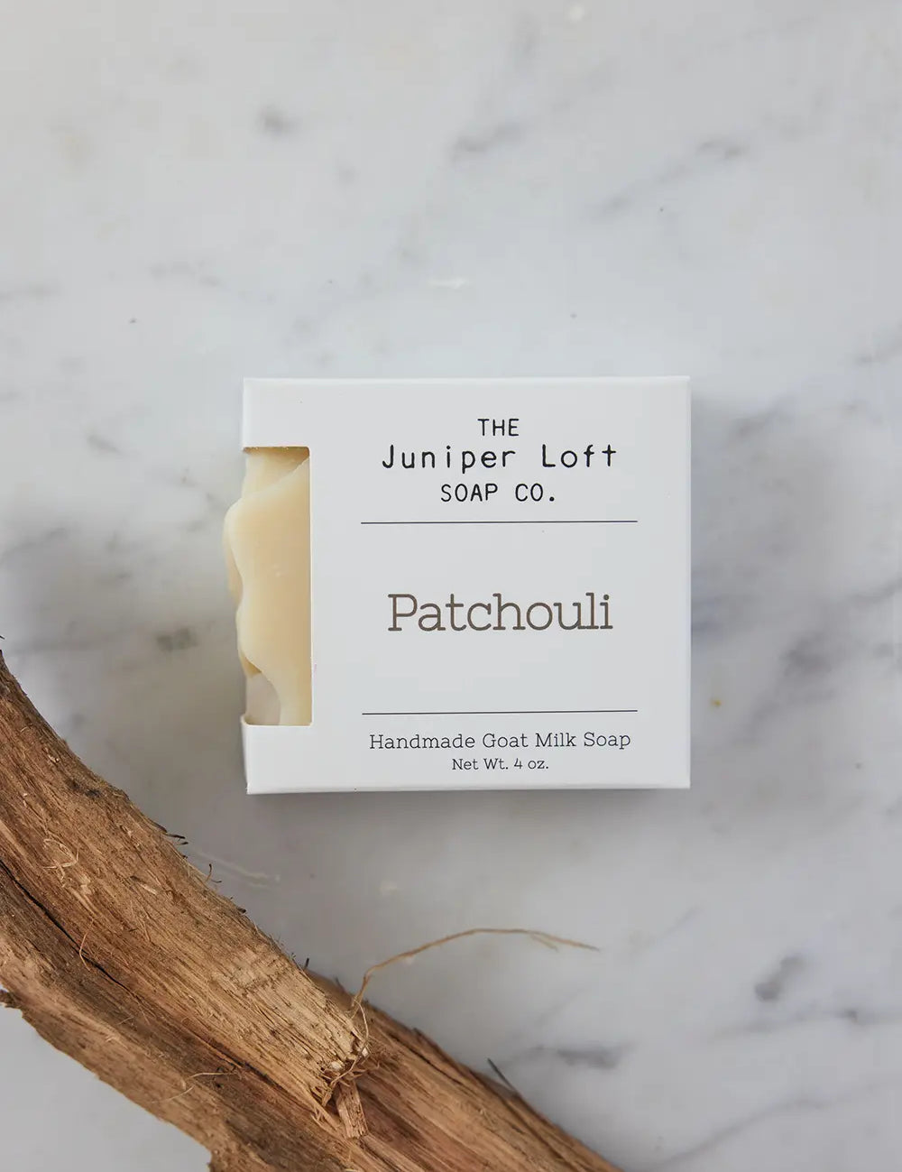 Bar of Patchouli soap from Juniper Loft Soap Company above a stick of patchouli