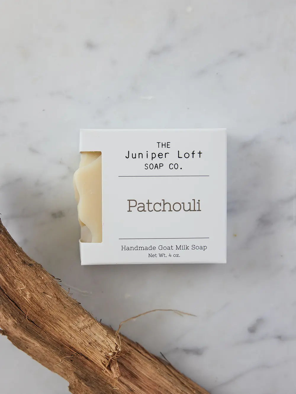Bar of Patchouli soap from Juniper Loft Soap Company above a stick of patchouli