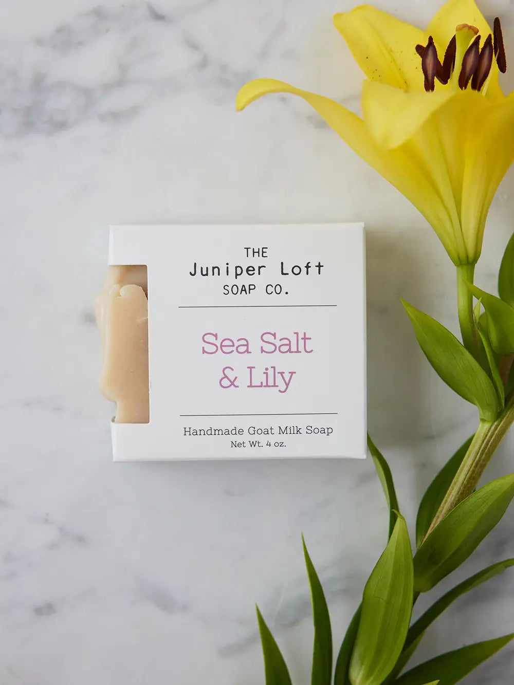 Bar of Sea Salt and Lily soap from Juniper Loft Soap Company beside a large yellow Asiatic Lily