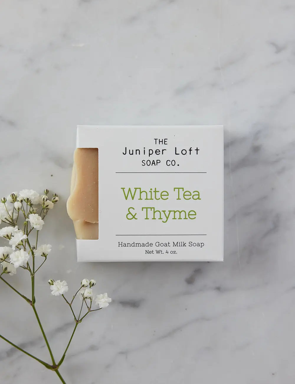 Bar of White Tea and Thyme soap from Juniper Loft Soap Company with a spring of baby's breath