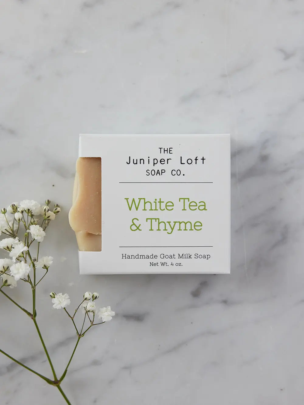 Bar of White Tea and Thyme soap from Juniper Loft Soap Company with a spring of baby's breath