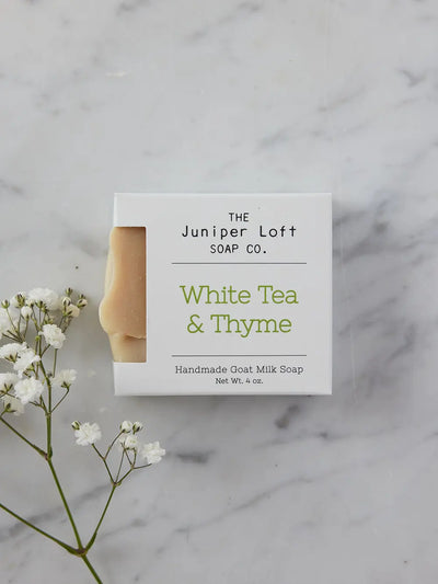 Bar of White Tea and Thyme soap from Juniper Loft Soap Company with a spring of baby's breath