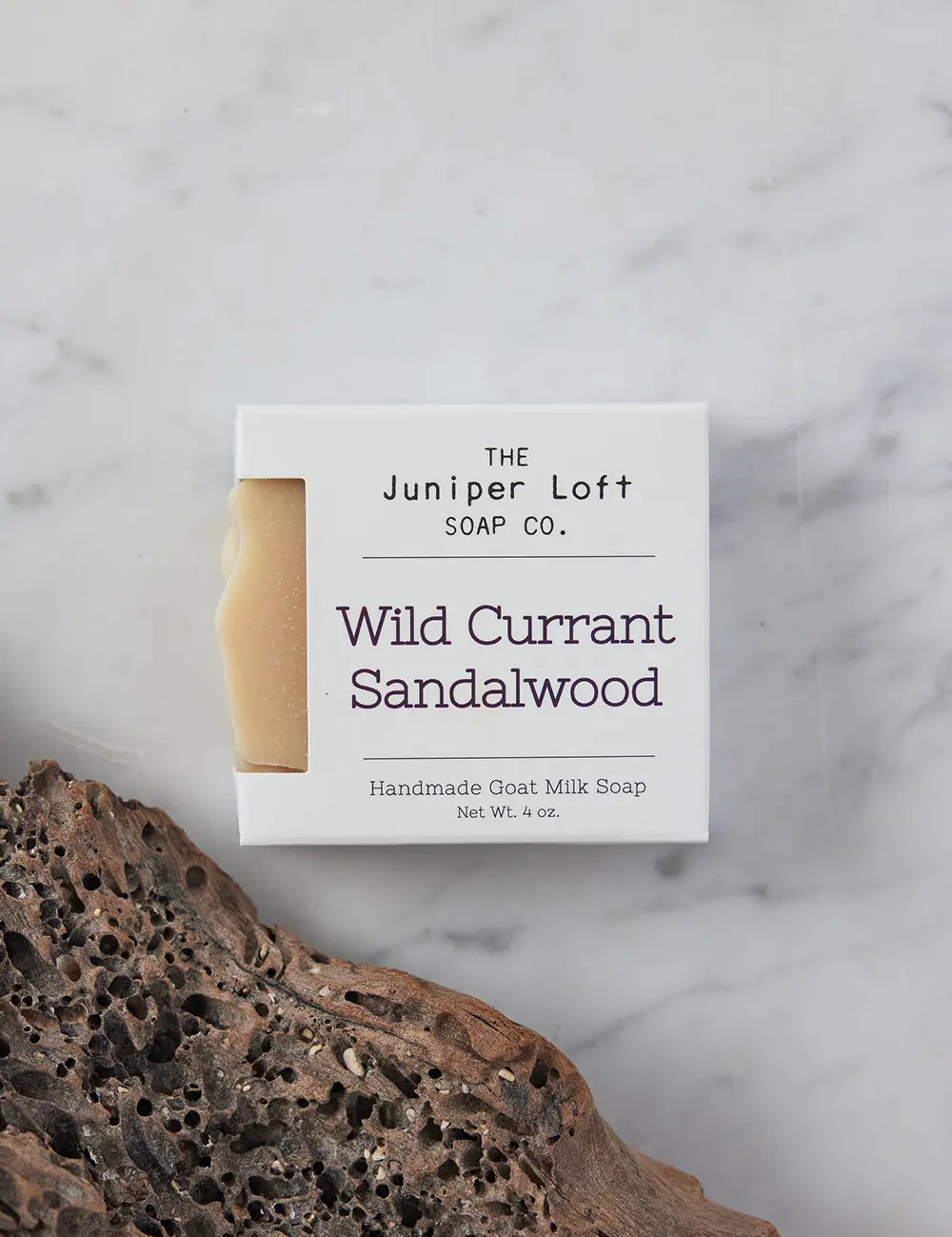 Bar of Wild Currant and Sandalwood soap from Juniper Loft Soap Company next to a porous piece of sandalwood