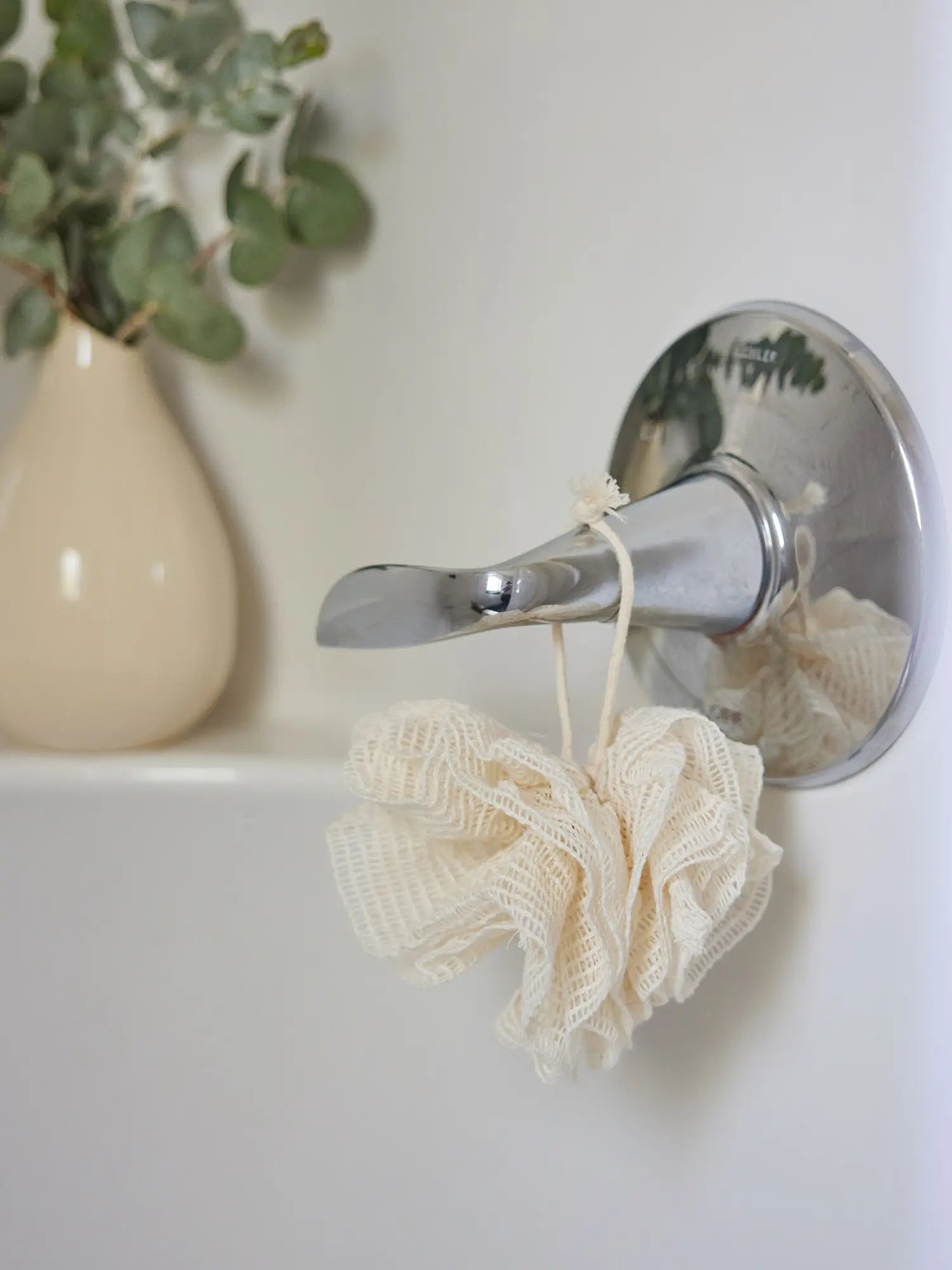 Ramie mesh pouf from Juniper Loft Soap Company hanging from a bathtub lever