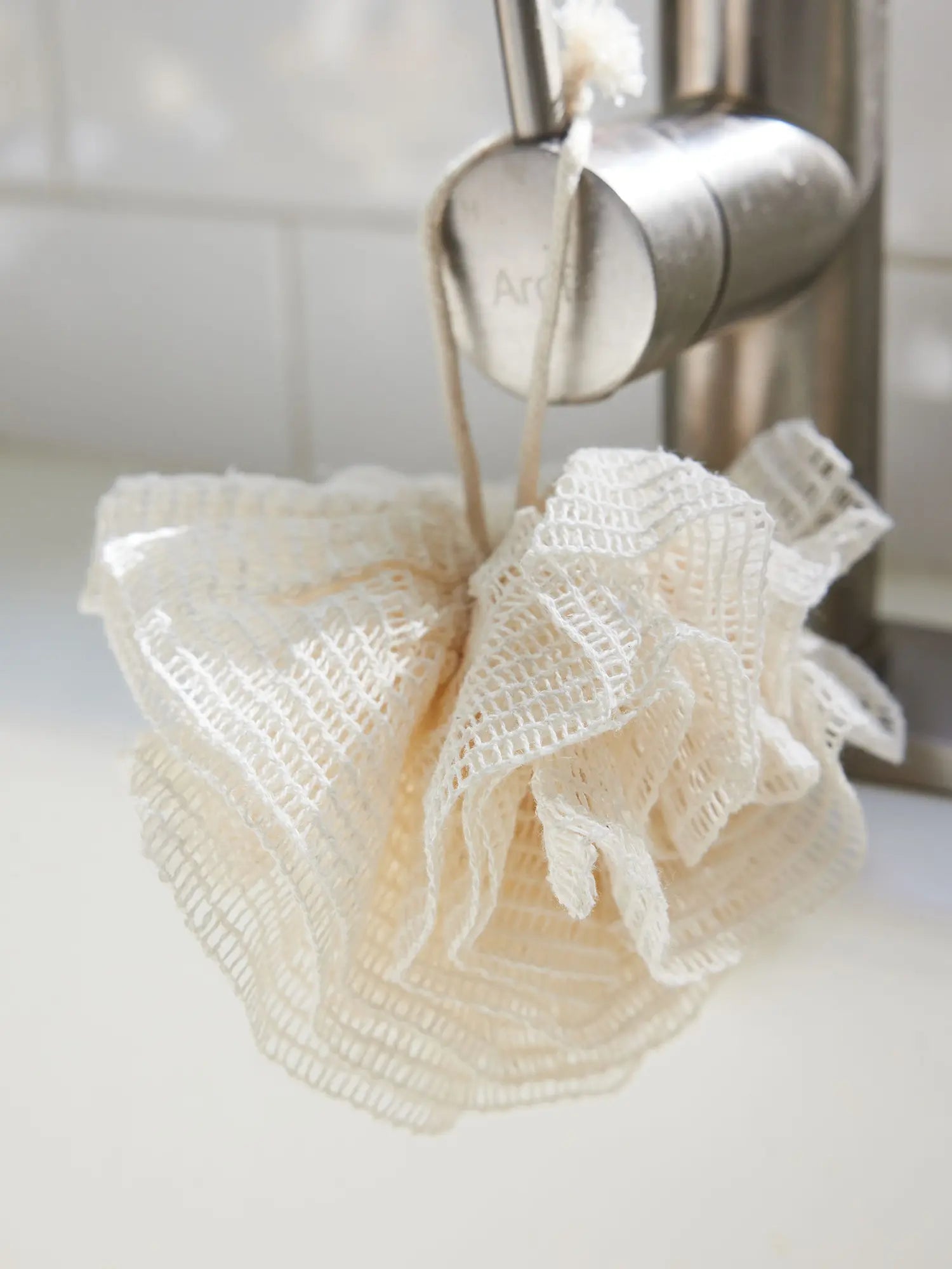 Ramie mesh pouf from Juniper Loft Soap Company hangs from a shower handle
