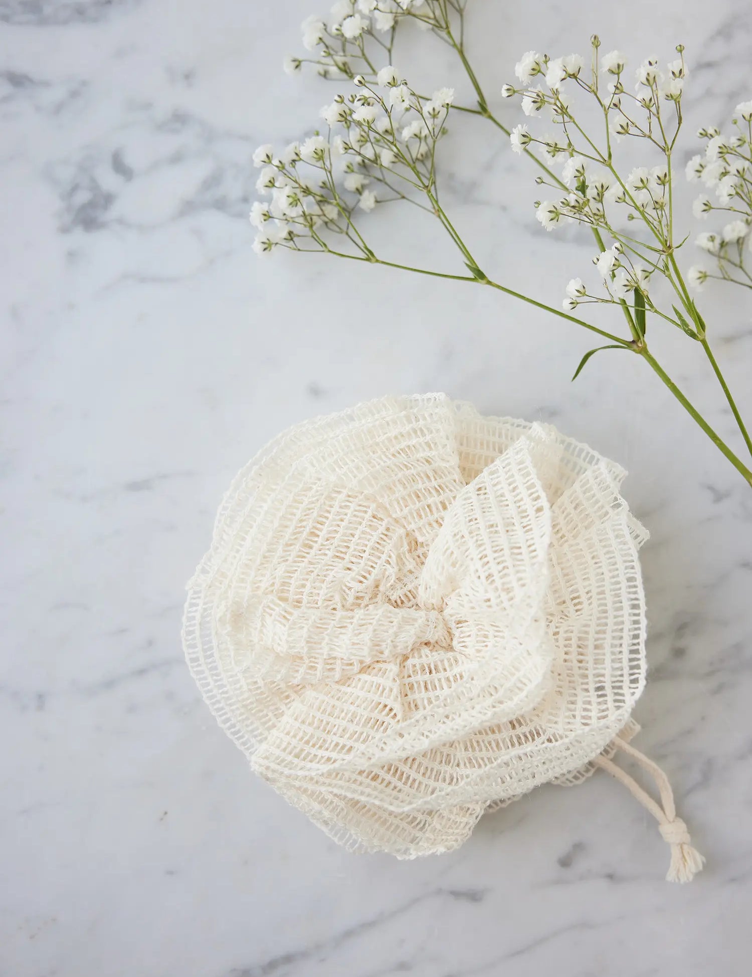 Ramie mesh pouf from Juniper Loft Soap Company on a gray marble countertop
