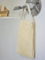Juniper Loft Soap Company sisal back scrubber hanging from a bathtub lever