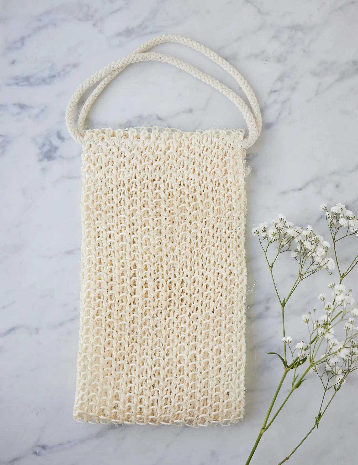 Juniper Loft Soap Company sisal back scrubber on a gray marble countertop with a sprig of baby's breath