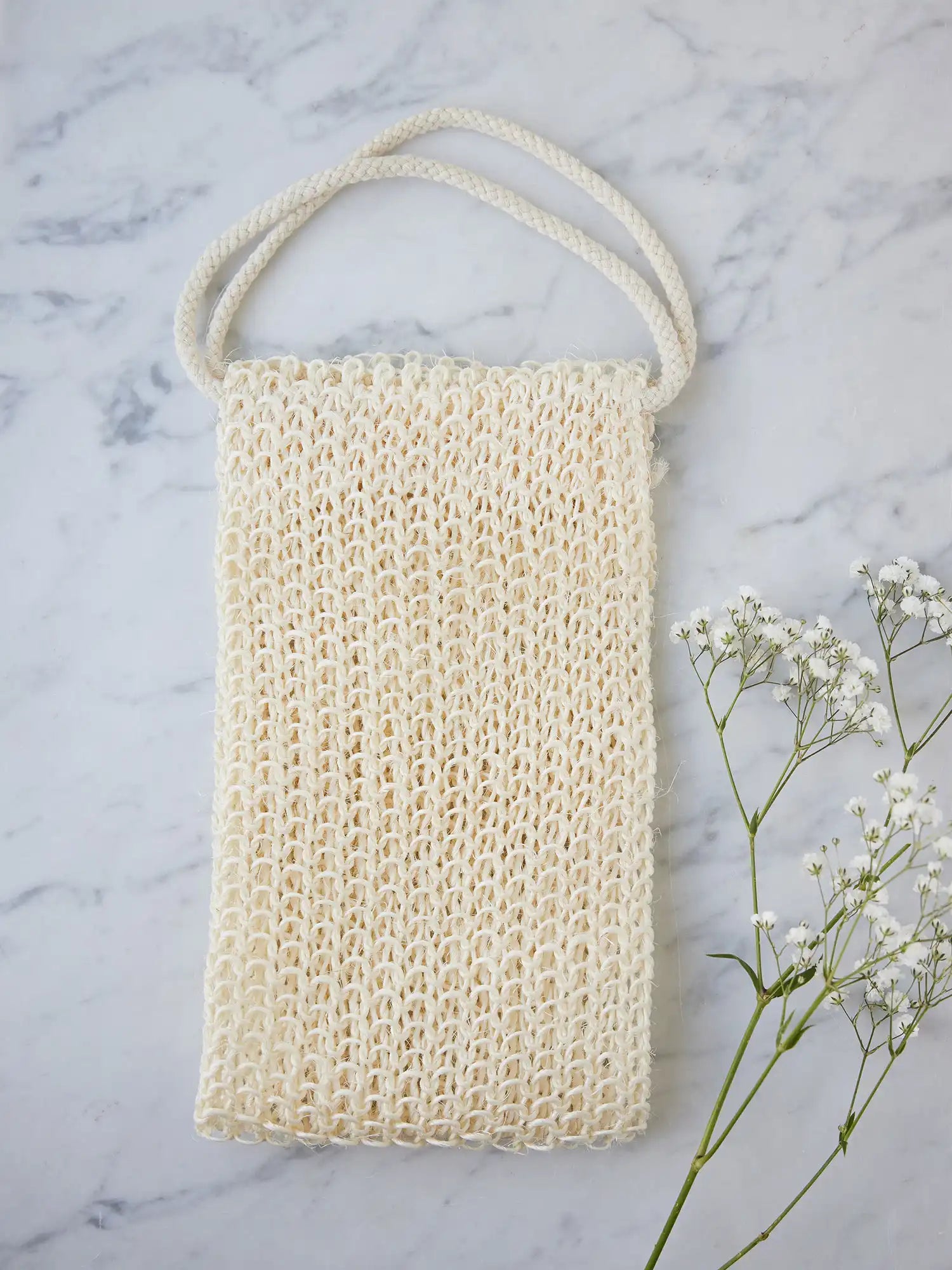 Juniper Loft Soap Company sisal back scrubber on a gray marble countertop with a sprig of baby's breath